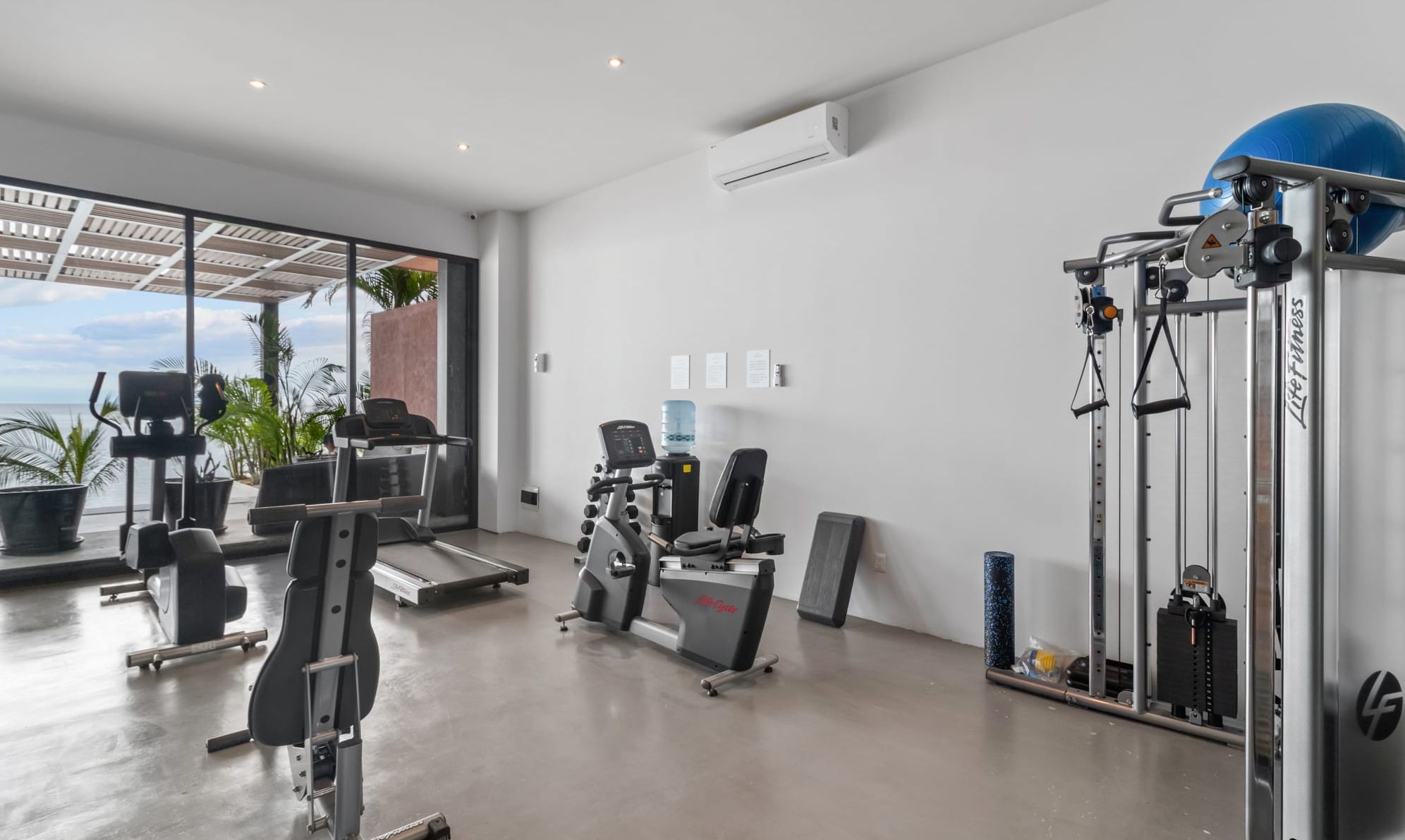 A gym with cardio machines, weightlifting equipment, and a large blue exercise ball.