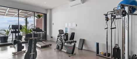 A gym with cardio machines, weightlifting equipment, and a large blue exercise ball.
