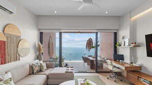 En moderne stue med en stor skydedør, der fører ud til en balkon med havudsigt.