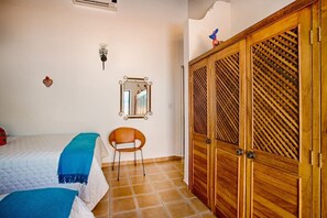 A bedroom with a bed, a chair, a wardrobe, and a mirror on the wall. - Villa Delfin: Golden Zone 3BR with Private Pool (Bucerías)