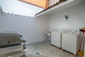 A laundry area with two washing machines, a sink, and a drying rack. - Villa Delfin: Golden Zone 3BR with Private Pool (Bucerias)