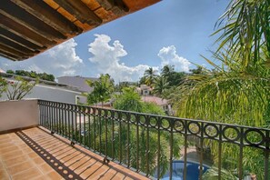 A balcony with a view of a swimming pool, palm trees, and a clear sky. - Villa Delfin: Golden Zone 3BR with Private Pool (Bucerías)