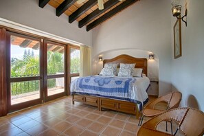 A bedroom with a bed, two wall-mounted lights, a wooden headboard, and a sliding glass door leading to a balcony. - Villa Delfin: Golden Zone 3BR with Private Pool (Bucerías)