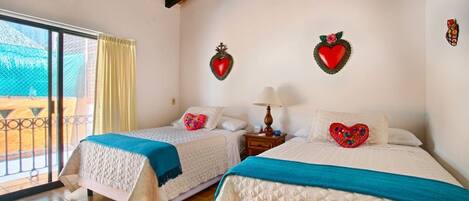 Habitación de hotel con dos camas, un balcón y decoración con forma de corazón en la pared.