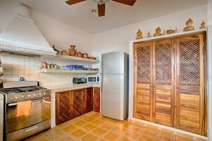 A kitchen with a gas stove, oven, microwave, and refrigerator. There are wooden cabinets and a tiled backsplash. - Villa Delfin: Golden Zone 3BR with Private Pool (Bucerías)