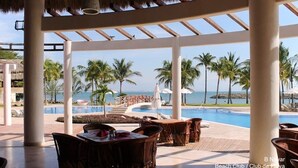 A beach club with outdoor seating and a pool overlooking the ocean.