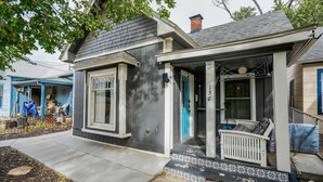 Une maison à deux étages avec un porche, un petit jardin devant et une boîte aux lettres.