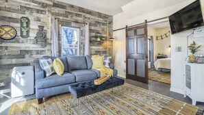 Un salon moderne avec un canapé gris, un tapis à motifs et un mur d’accent en bois.