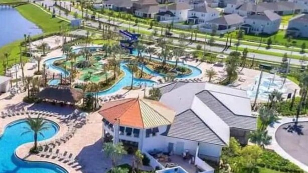 Um resort com piscina central, parque aquático e um edifício com telhado vermelho.