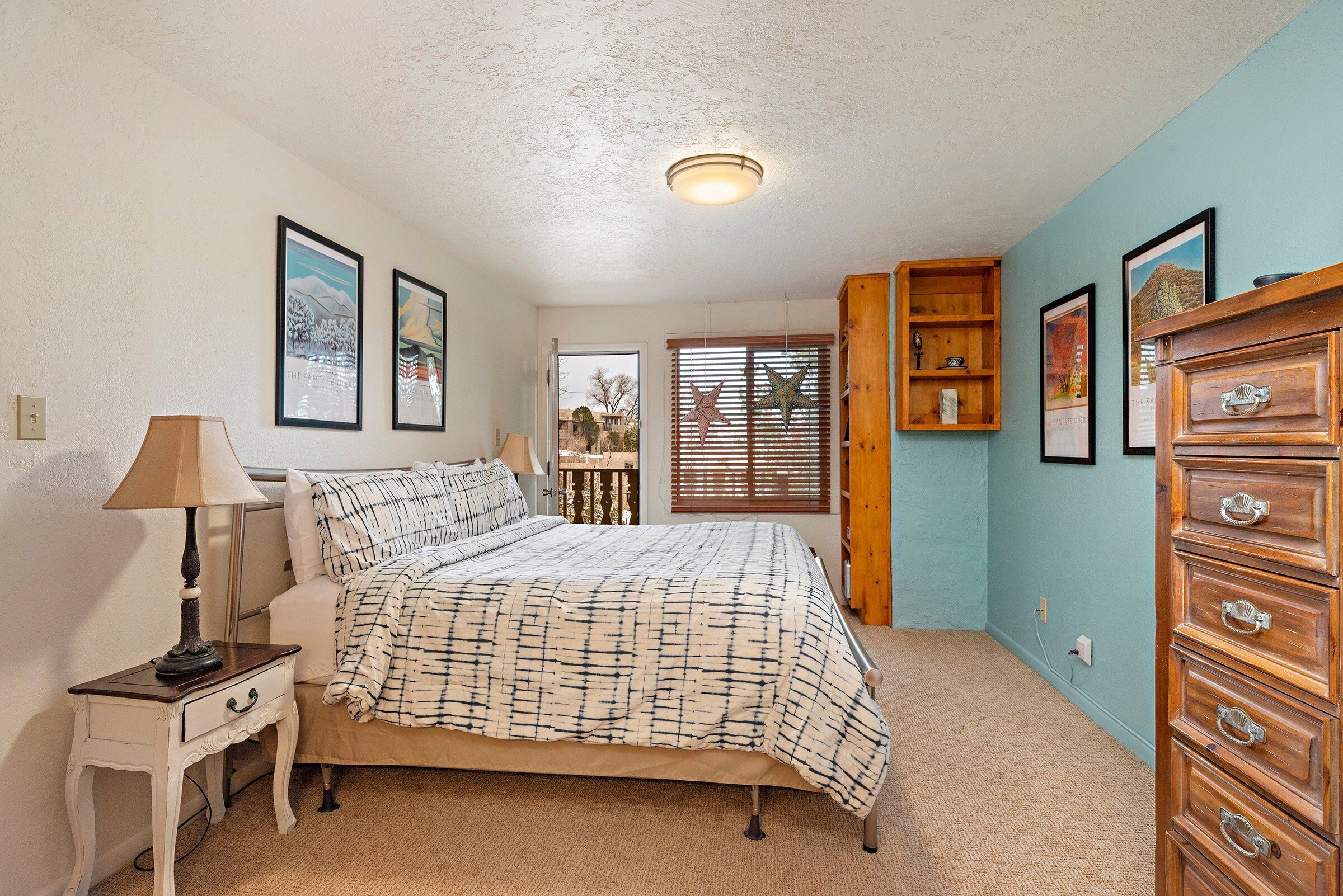 A bedroom with a bed, a nightstand, a dresser, and a window with blinds.