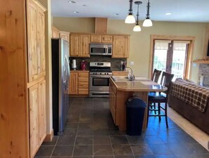 Enjoy cooking in this well-equipped kitchen with a large island, sink, and bar stools.