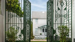A gated entrance with a brick pathway leading to a lawn area.