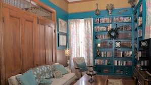 A cozy living room with a wooden sofa, a coffee table, and a bookshelf filled with books and decorative items.