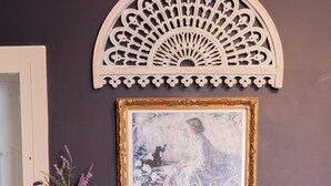 A room with a white fireplace, a painting above it, and a floral arrangement on the mantel.