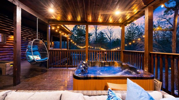A wooden deck with a hot tub, hanging chairs, and string lights. - 5Kings | Pool Table, Shuffleboard, Playset, Putt Putt | 2min to New Casino! (Broken Bow)