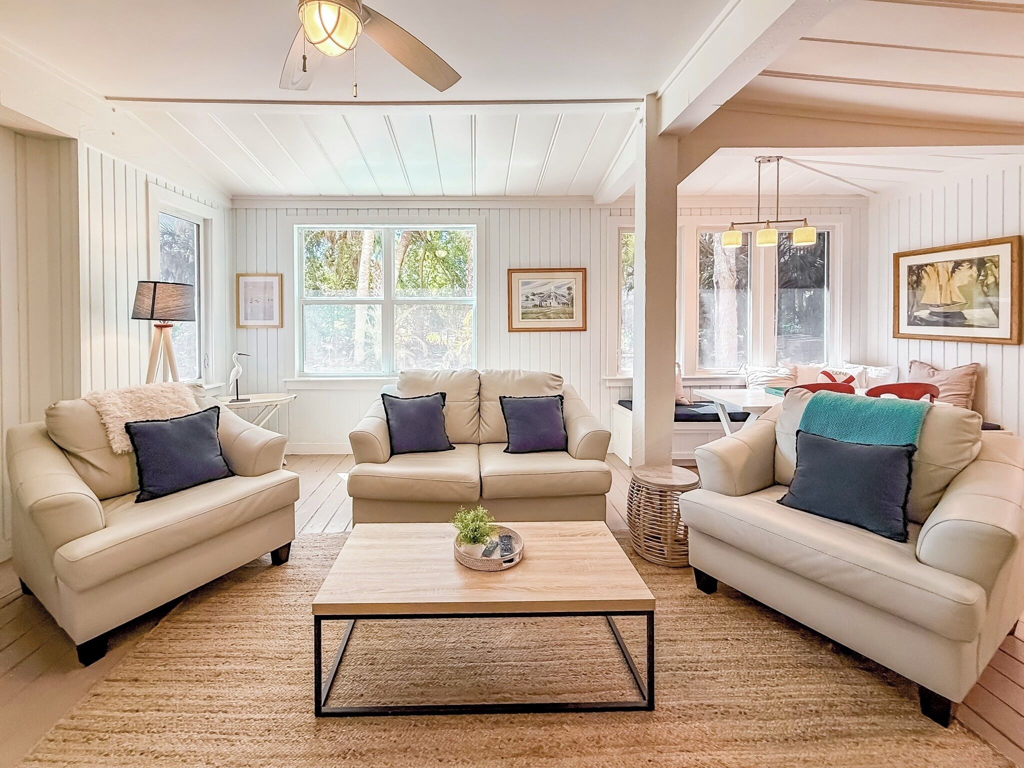A spacious living room with two beige sofas, a coffee table, and a ceiling fan.
