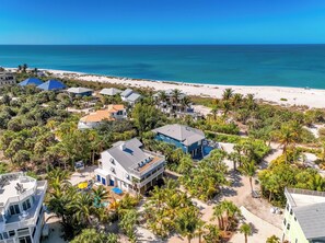 A coastal residential area with multiple houses, a beach, and a clear view of the ocean.