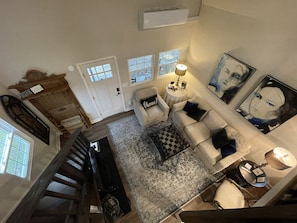 A spacious living area with a high ceiling, a staircase, and a view of the outdoors.
