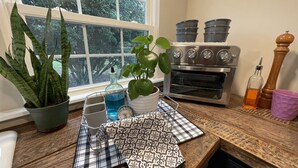 Una cocina con ventana, estufa, pileta y diversos utensilios.