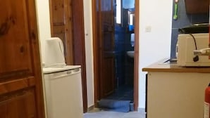 A narrow kitchen with wooden cabinets, a white refrigerator, and a sink. - Nostalgia (Skiathos)