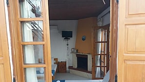 A cozy room with a bed, a small table, a television, and a fireplace. - Nostalgia (Skiathos)