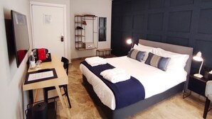 A modern hotel room with a large bed, a desk with a computer, a chair, a wardrobe, and a TV. - The Manoel Hotel (Valletta)