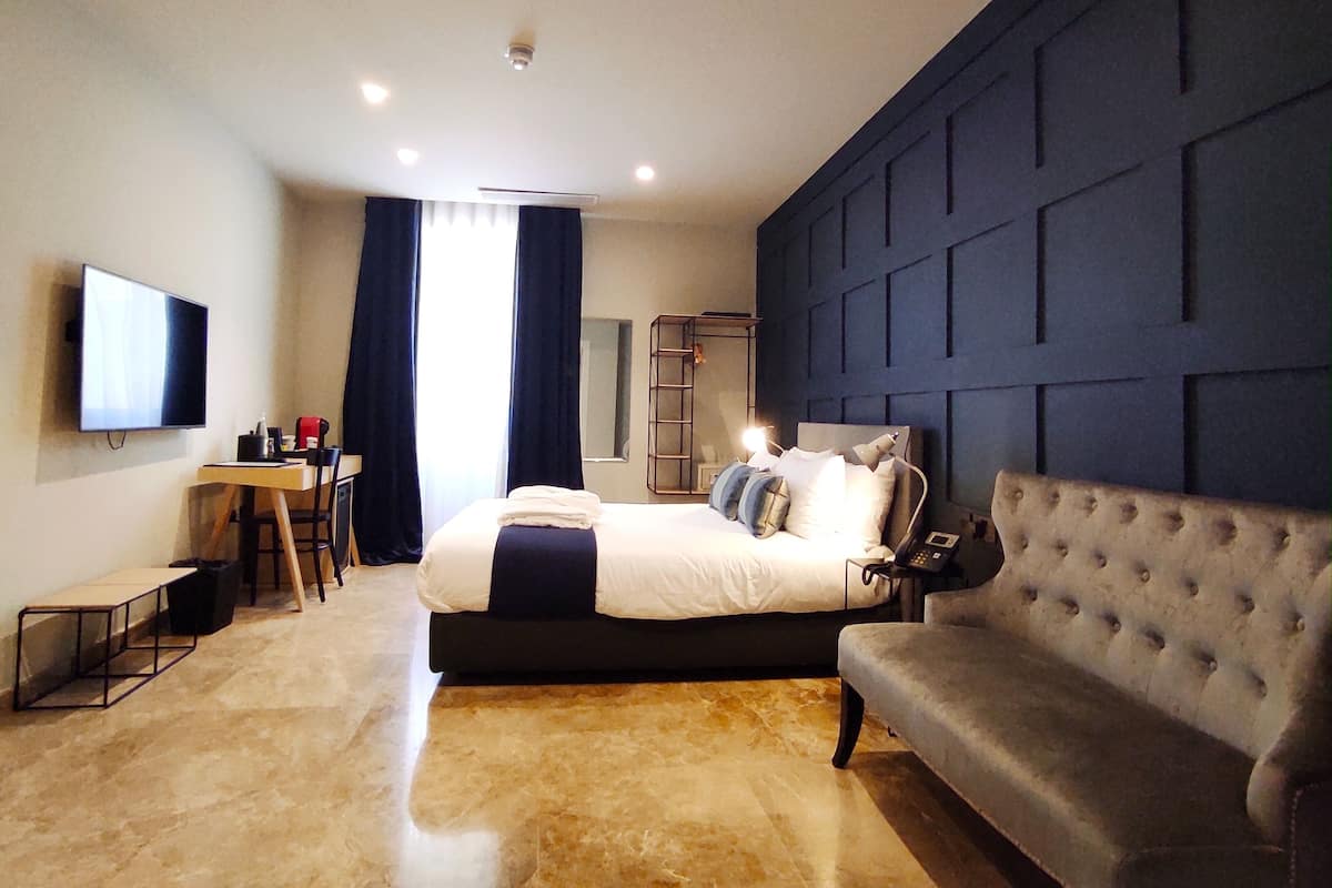 Ein modernes Hotelzimmer mit einem großen Bett, einer Couch, einem Schreibtisch und einem Fernseher.