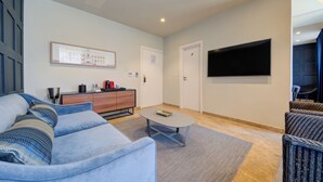 A modern living room with a sofa, coffee table, and a flat-screen TV mounted on the wall. - The Manoel Hotel (Valletta)