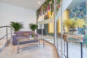 Un vestíbulo moderno con un sofá morado, una mesa de centro y plantas en macetas.