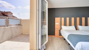 Ein Hotelzimmer mit Balkon, einem Bett mit Holz Kopfteil und einem großen Fenster.