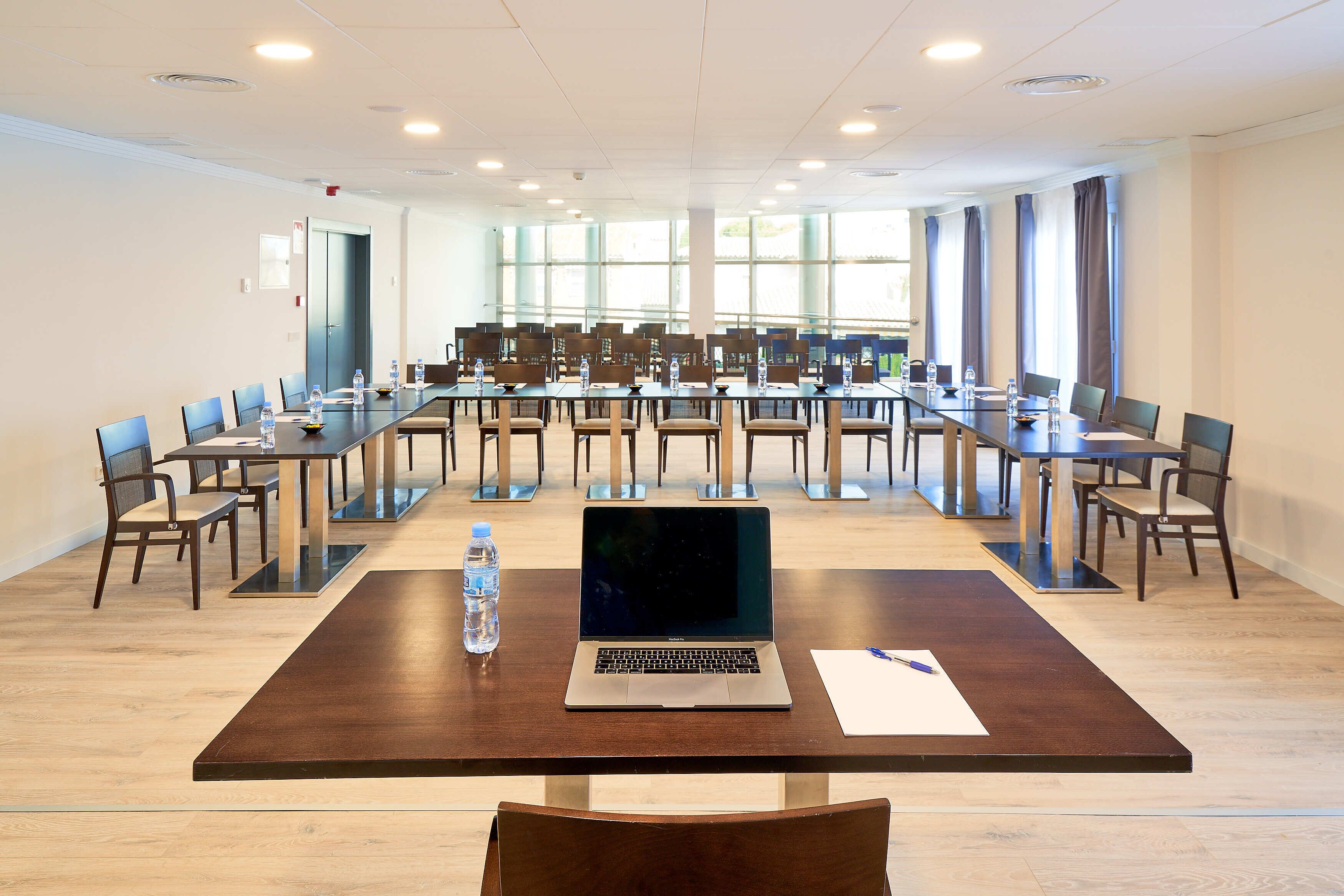 A conference room with a long table, chairs, and a laptop.