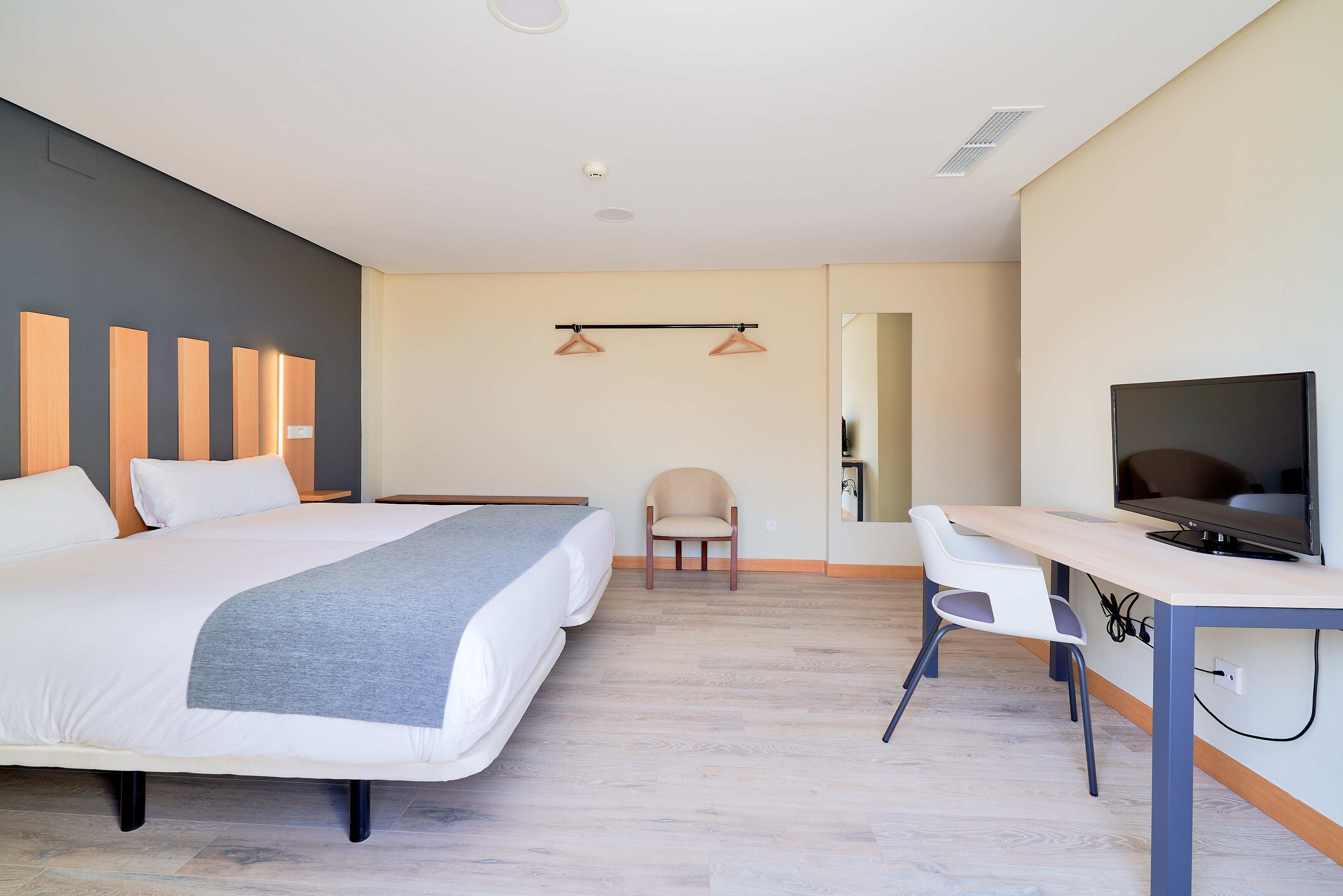 Habitación de hotel con cama, escritorio, televisión y silla.