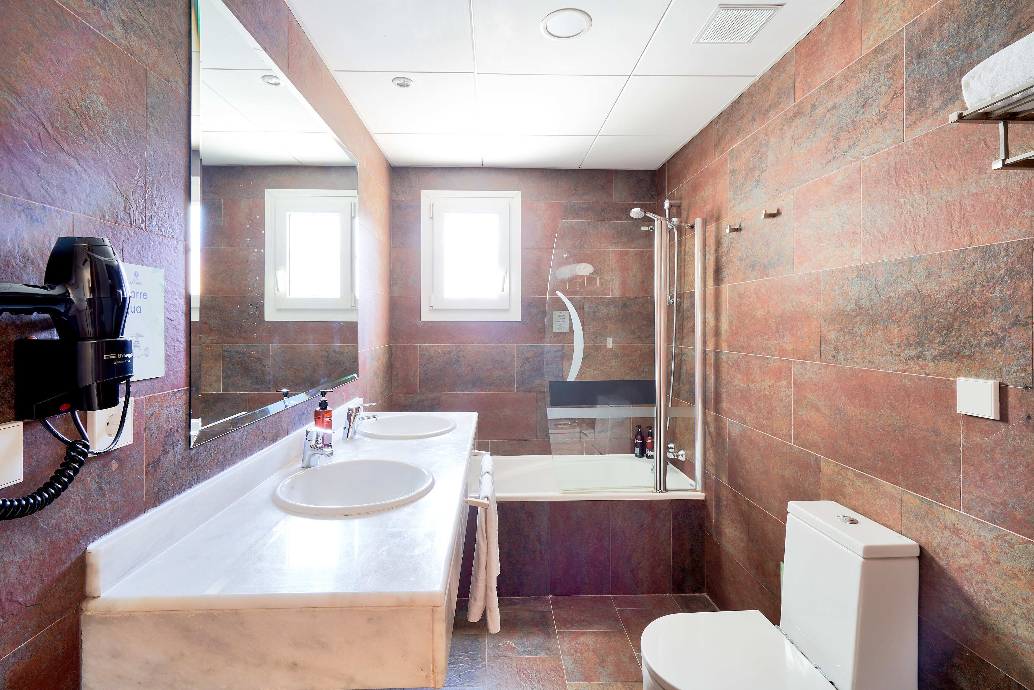 Un baño moderno con dos lavamanos, ducha e inodoro.