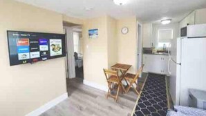 A compact kitchen with a refrigerator, a microwave, and a sink. There is a dining area with a table and chairs.