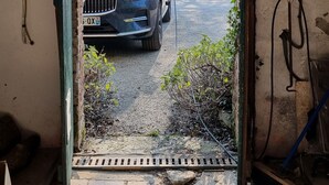 A car parked outside a building with a visible door frame and a window.