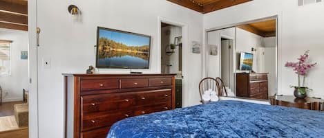 Un dormitorio con cama, cómoda, televisor y espejo.