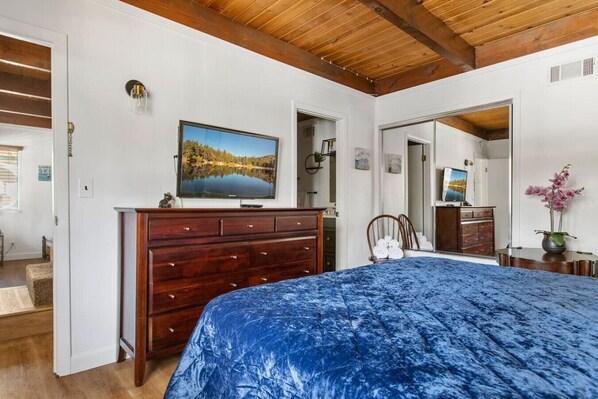 Un dormitorio con cama, cómoda, televisor y espejo.