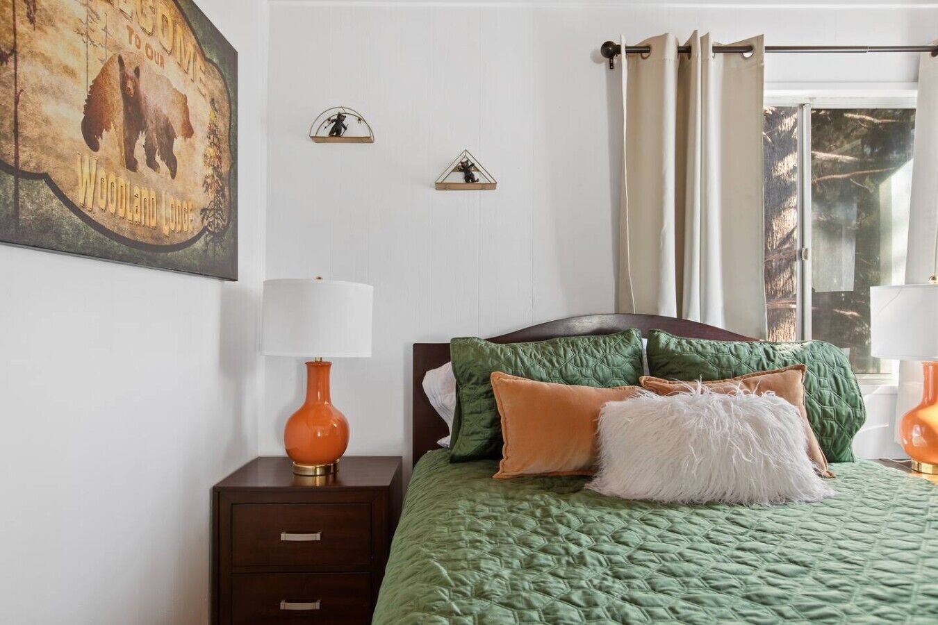 A bedroom with a bed, a nightstand, a lamp, and a window with curtains.