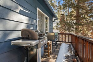 Een terras met een barbecue, een tafel en stoelen.