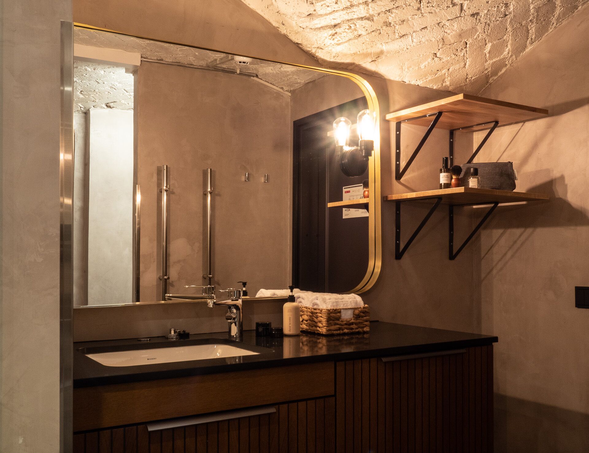 A bathroom with a large mirror, a sink, a towel, and a shelf with toiletries.