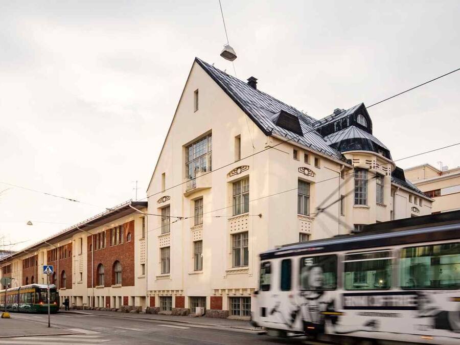 A street with a tram, a building with a triangular roof, and a sign indicating no parking.