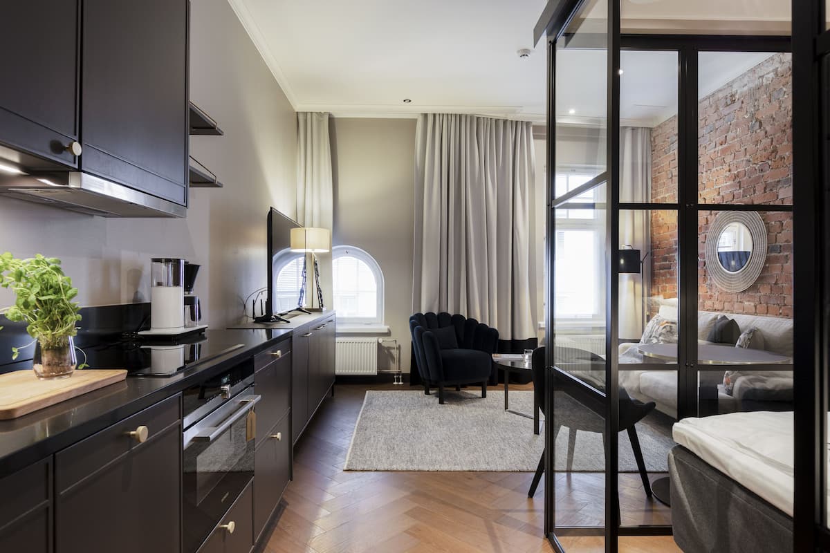 A modern kitchen with dark cabinetry, a coffee machine, and a plant on the counter.
