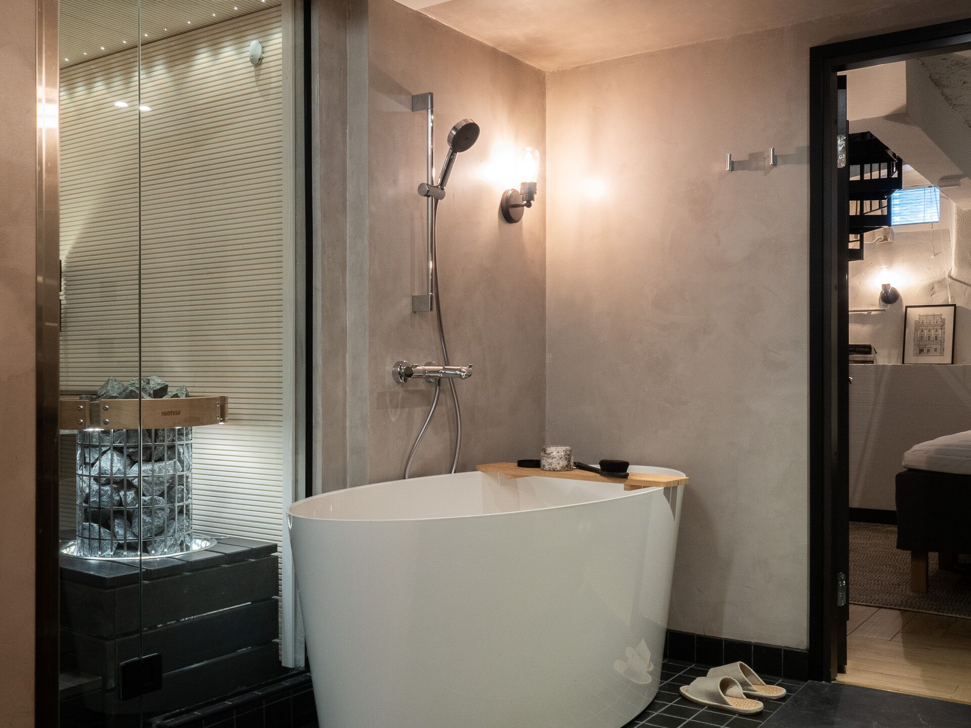 A modern bathroom with a freestanding bathtub, a glass shower enclosure, and a visible staircase leading to another room.