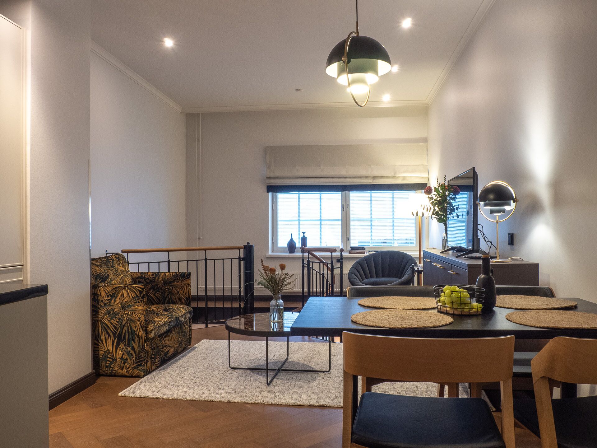 A modern dining area with a round table, chairs, and a hanging light fixture.