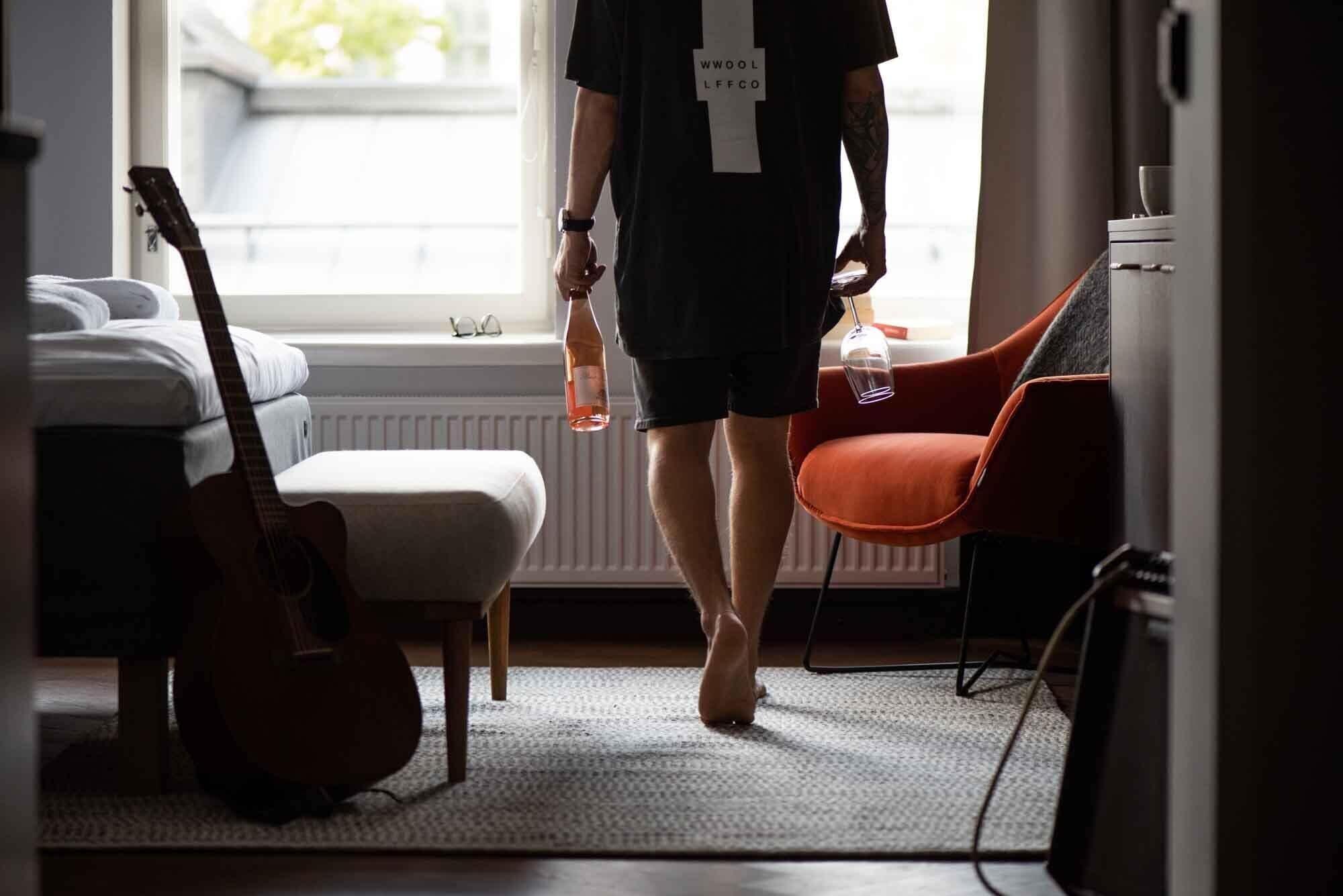 A room with a bed, a guitar, a chair, and a window.