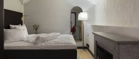 Une chambre à coucher avec un lit, une cheminée et une vue sur un couloir.