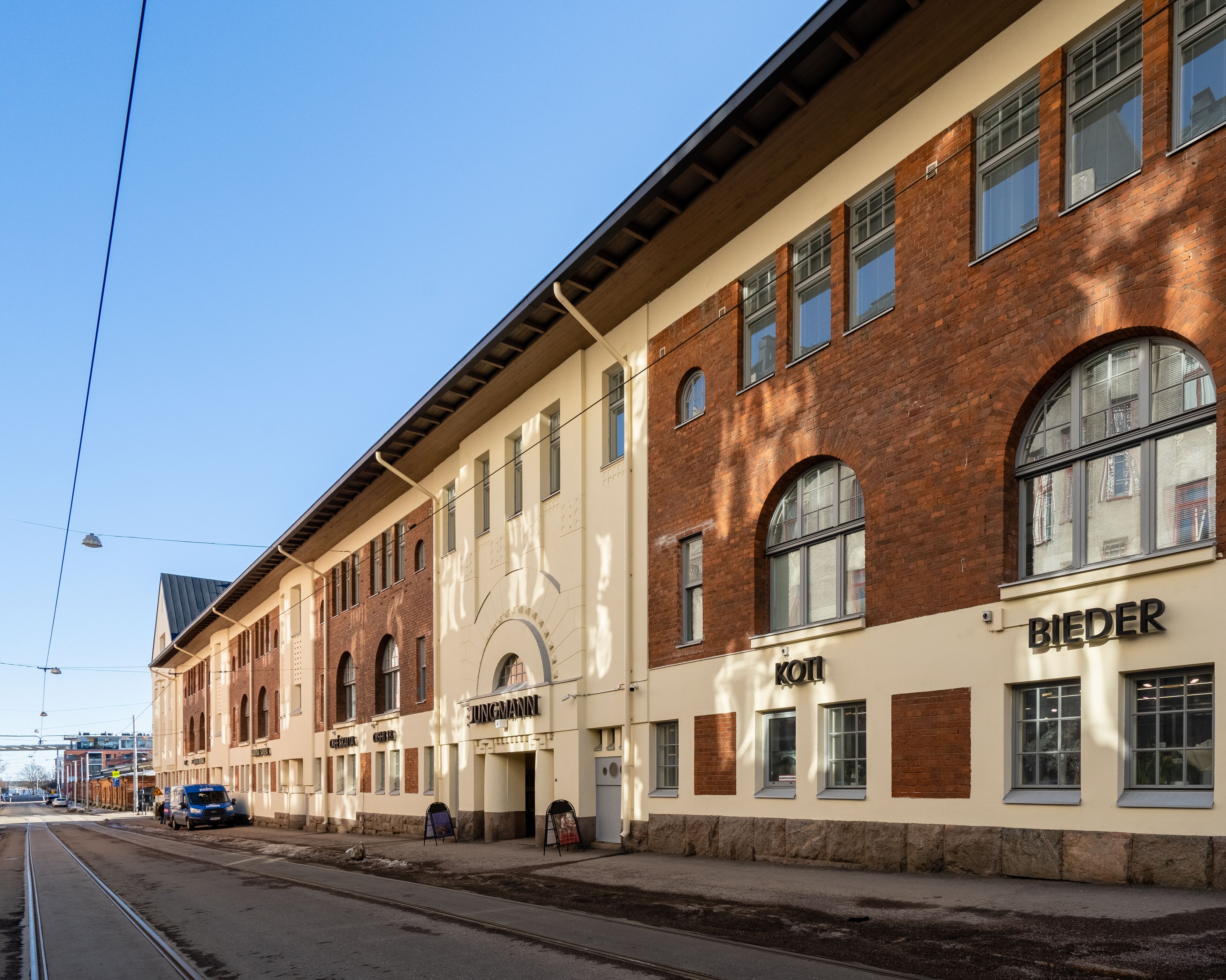 A train station building with multiple windows and a sign reading "KOTI".
