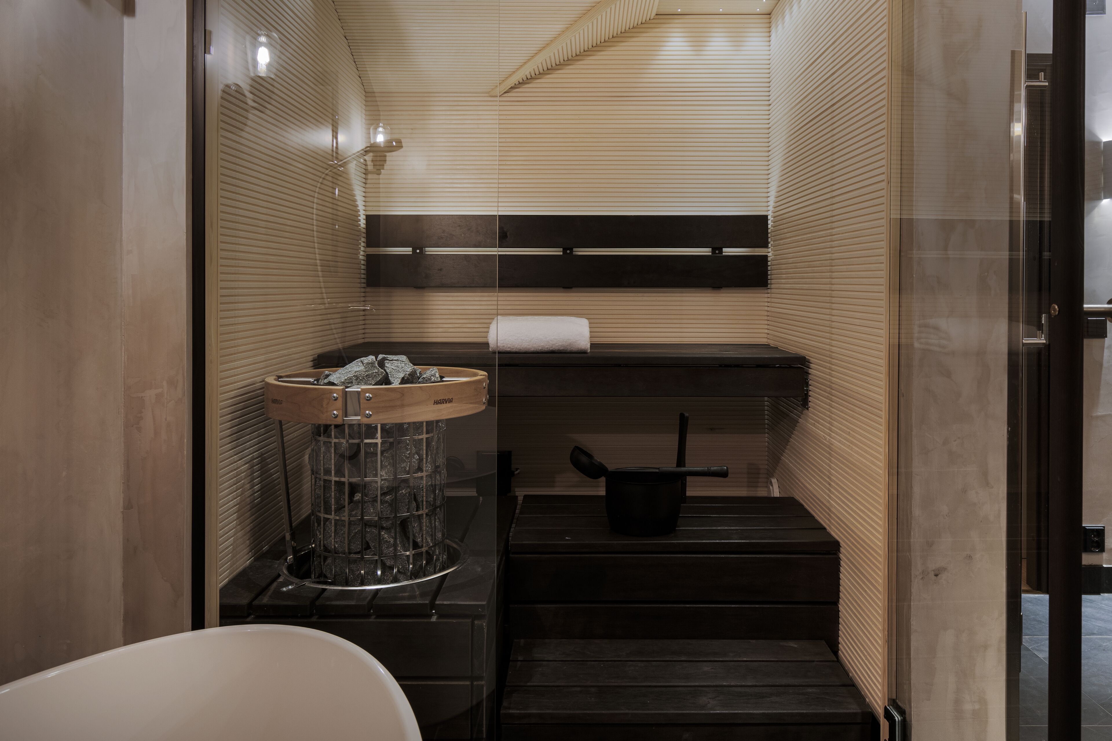 A compact bathroom with a sink, a towel rack, and a small step leading to a shower area.