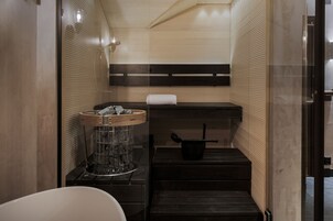 Un bagno compatto con lavandino, porta asciugamani e un piccolo scalino che conduce alla zona doccia.