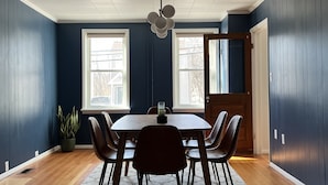 A dining area with a round table, chairs, a potted plant, and a ceiling fan. - Historic Hudson Valley 1850 Brick Home (Saugerties)